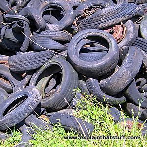 A heap of exhausted, discarded rubberized vehicle tires piled along with lawn.